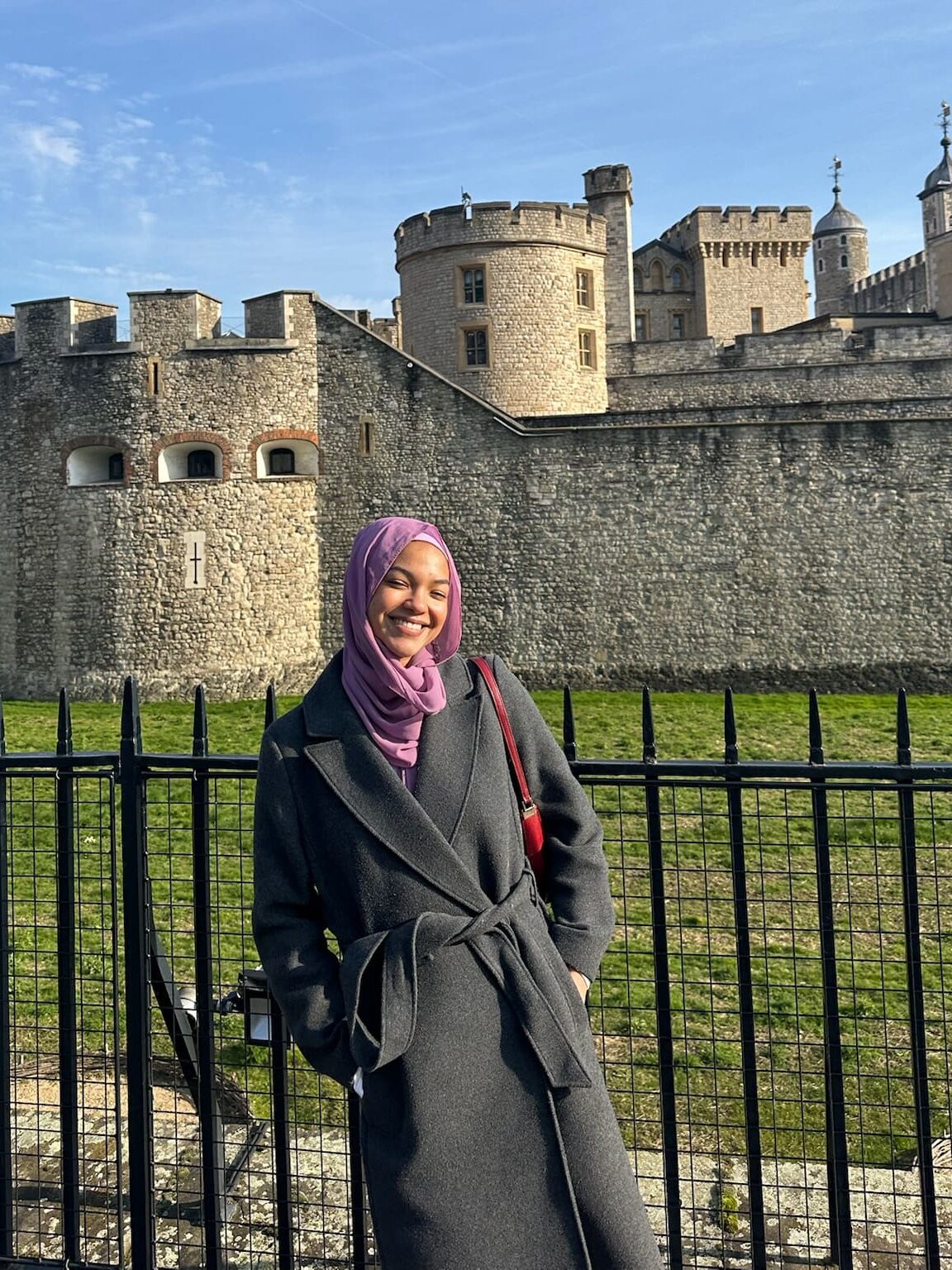 A student standing along a fence in front of the medieval tower of London.