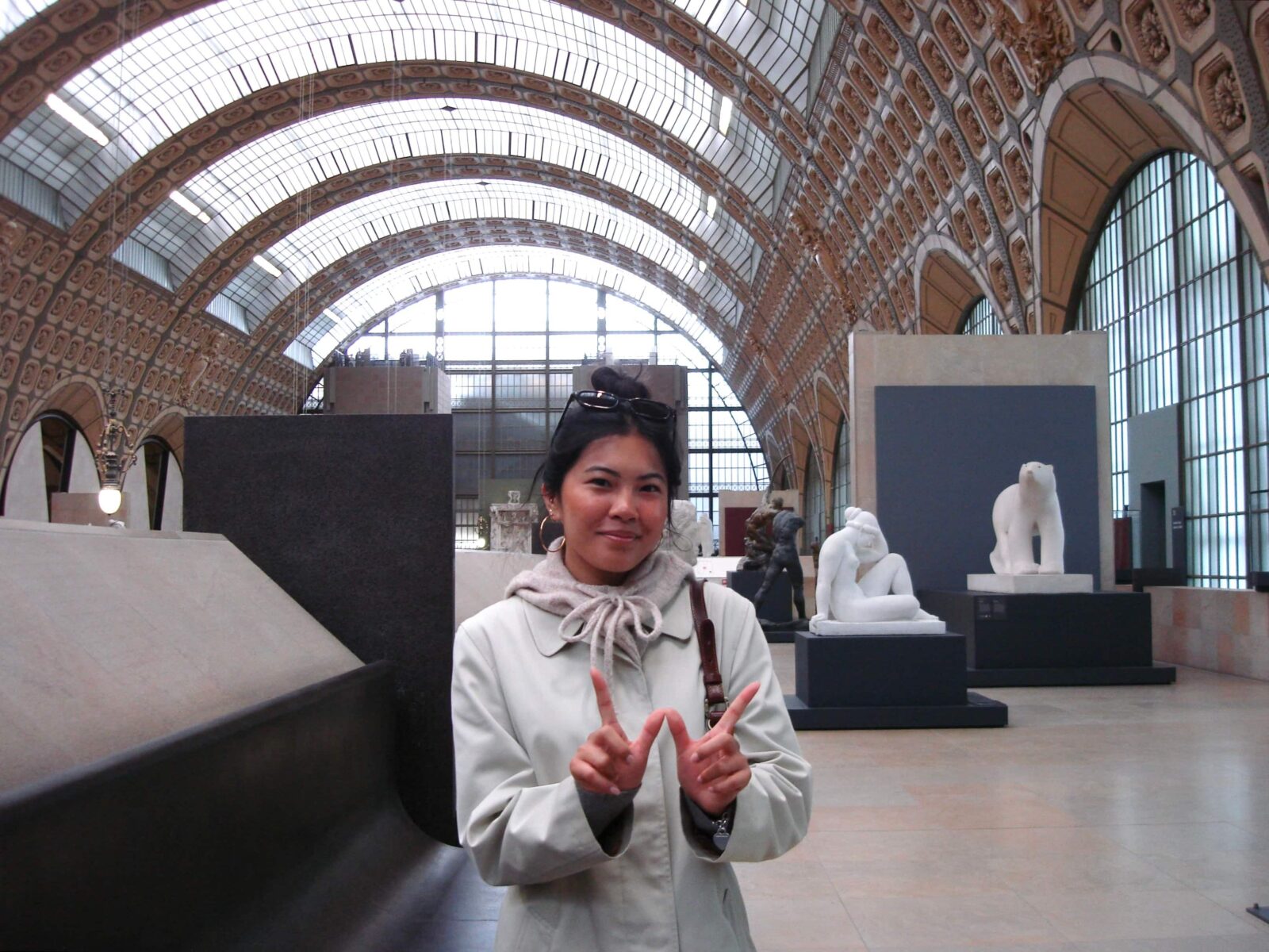 A student posing in a large sculpture museum, making a "W" with her fingers.