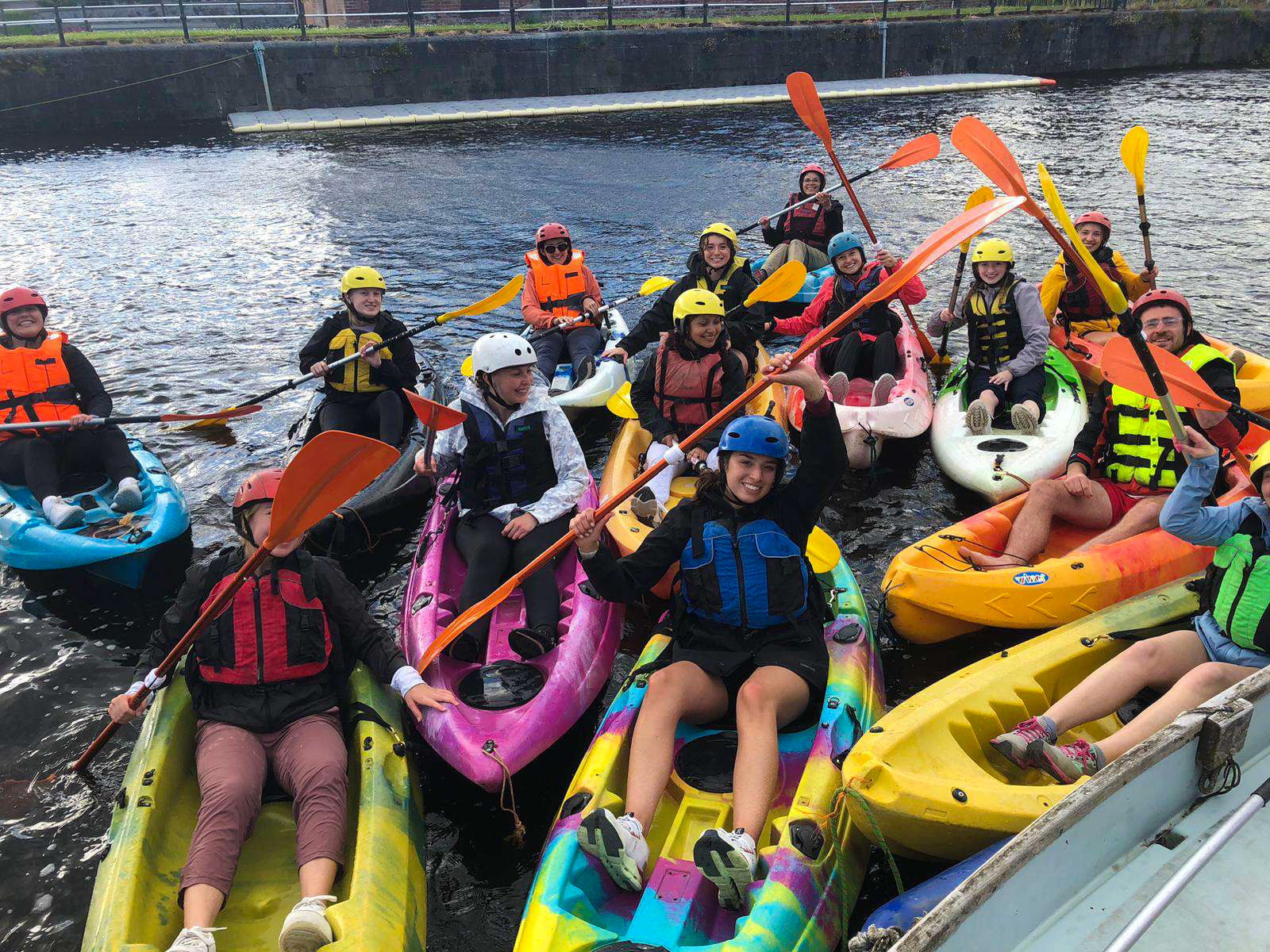 A group of students posing in brightly-colored kayaks.