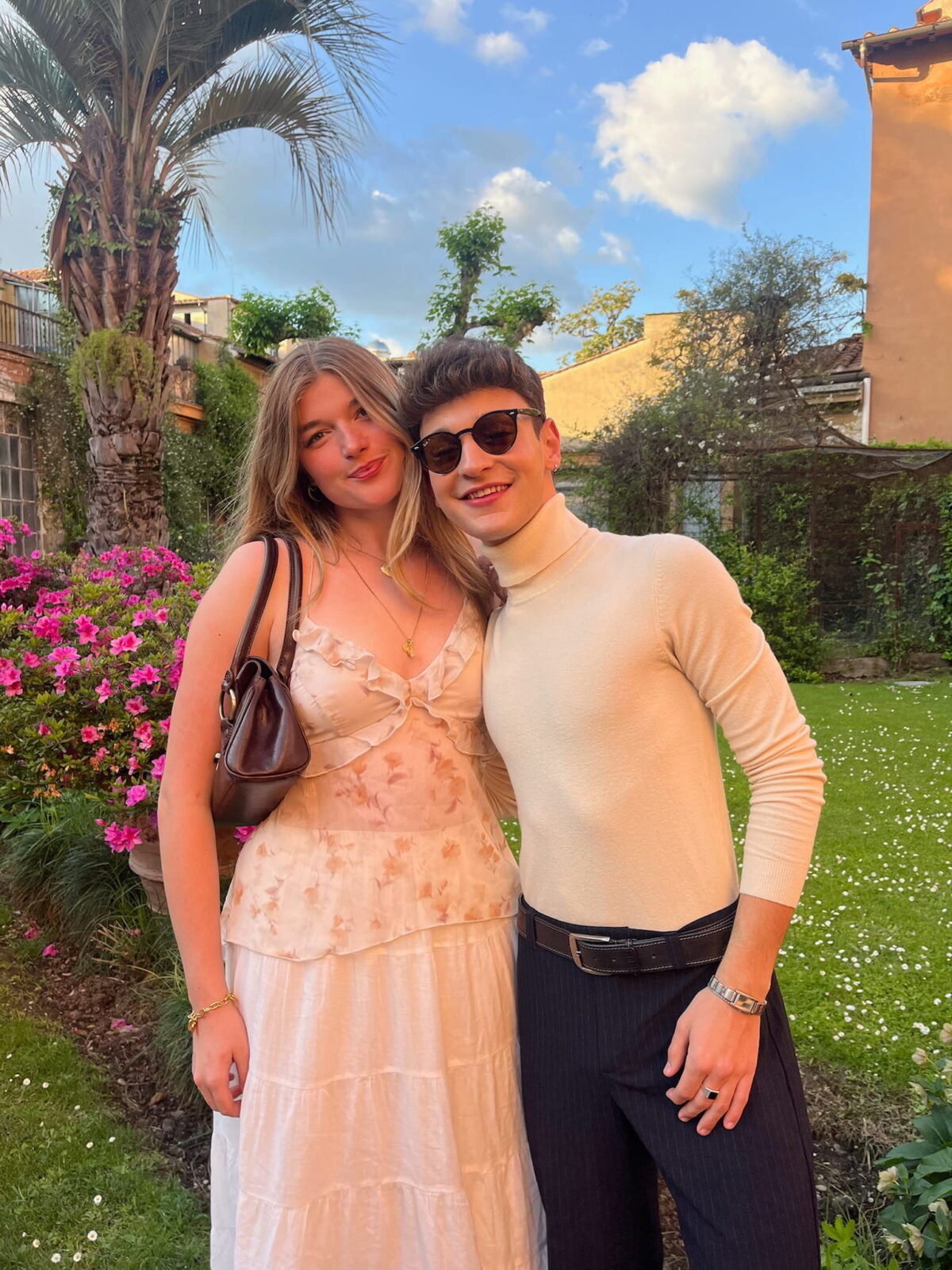 Two students in fancy attire, posing together in a beautiful courtyard garden.
