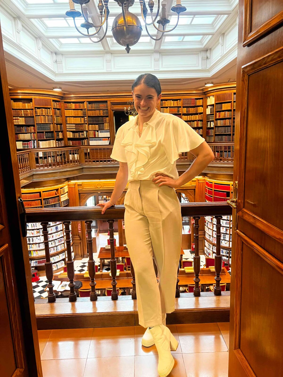 A student leaning against an indoor balcony inside an ornate library.